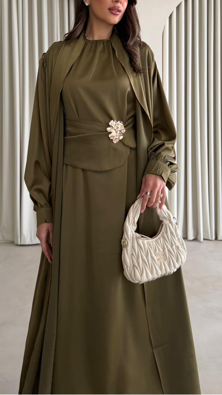 Woman in a green outfit holding a white handbag against a neutral background